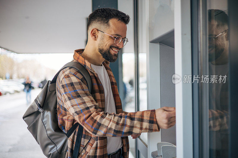 一个有魅力的男人用信用卡从自动取款机取钱。