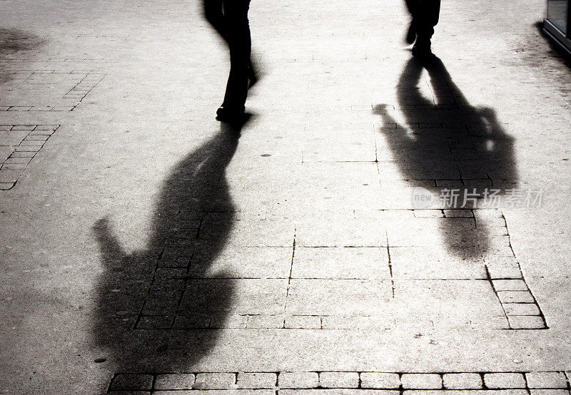 一个男人的影子在有图案的人行道上