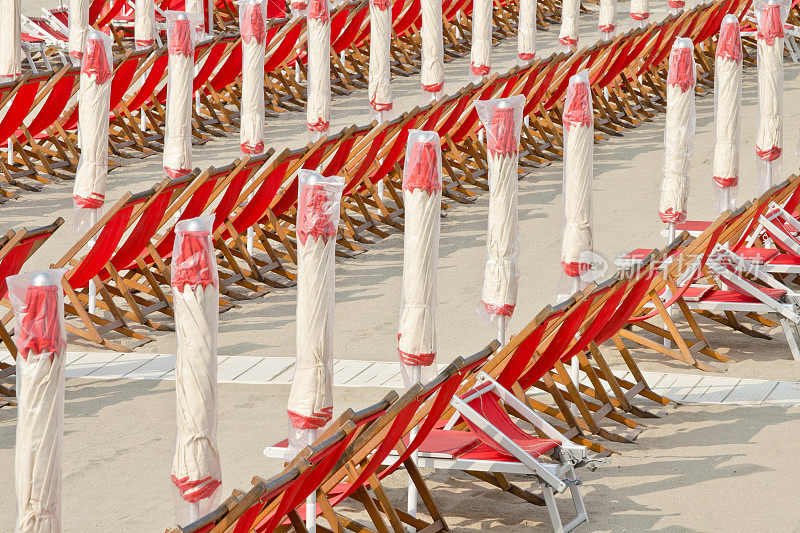 沙滩，红色遮阳伞和躺椅排成一排