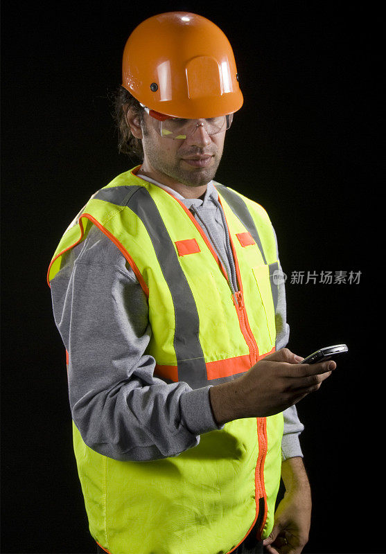 建筑工人交谈，安全帽，安全背心和手机