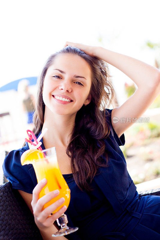 年轻女子拿着一杯橙汁在户外微笑