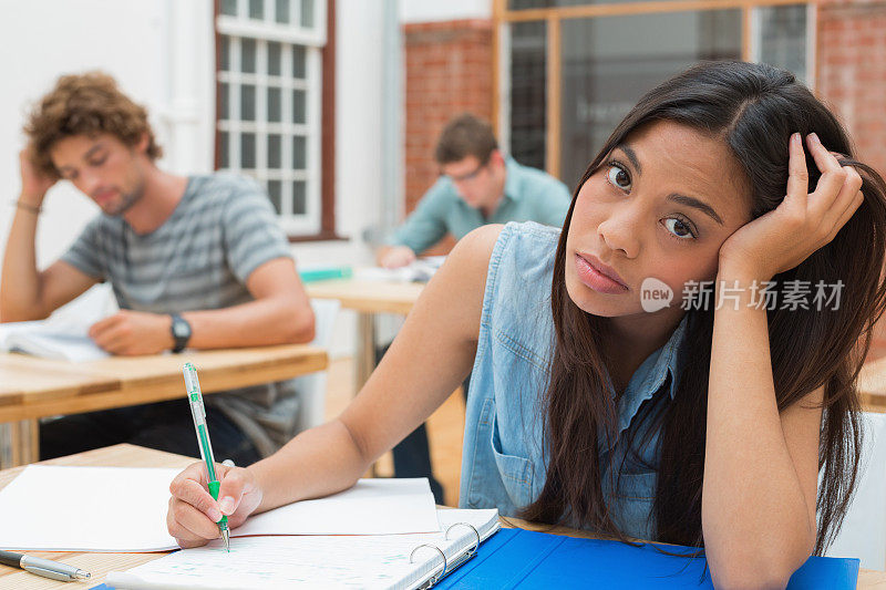 焦虑的学生在课堂上写她的文件夹