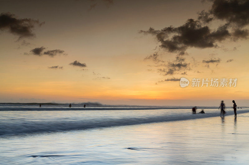 海滩上的人们在夕阳下游泳