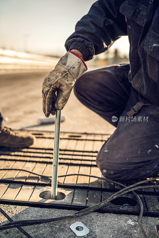 手动工人在道路上安装金属条的特写。