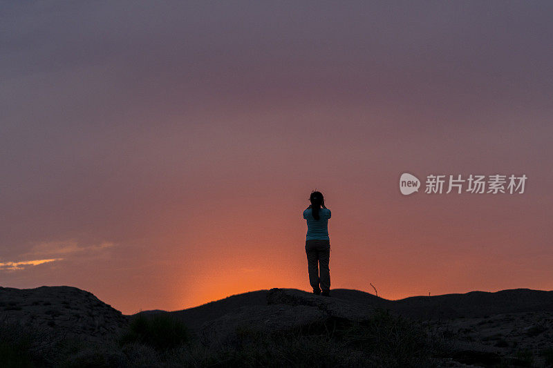 女孩在山顶拍摄日落