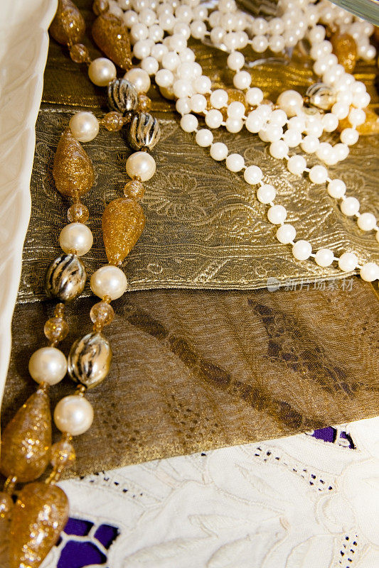 老式的珍珠和珠子放在老式的桌布上。