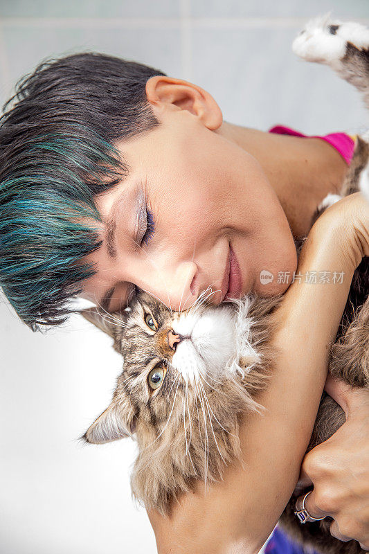 美丽的女人爱抚她可爱的西伯利亚猫在浴室