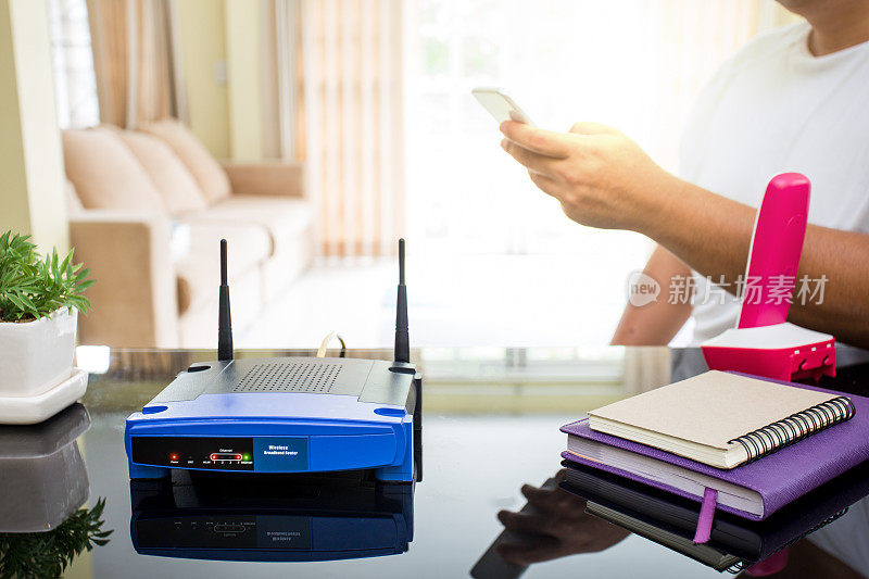 一个无线路由器和一个年轻人使用智能手机在客厅在家里的特写