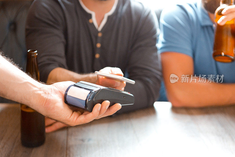 男子在酒吧使用近场通讯技术通过智能手机付款