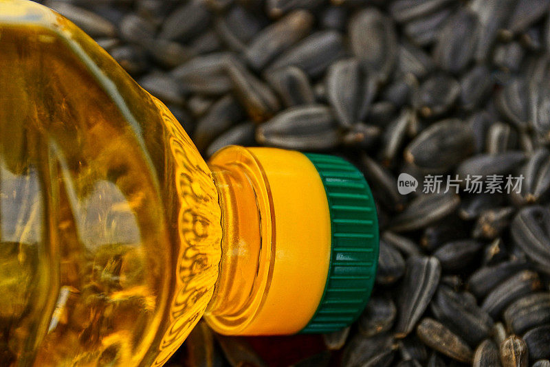 透明的瓶子上有黄色的葵花籽油和一堆黑色的种子
