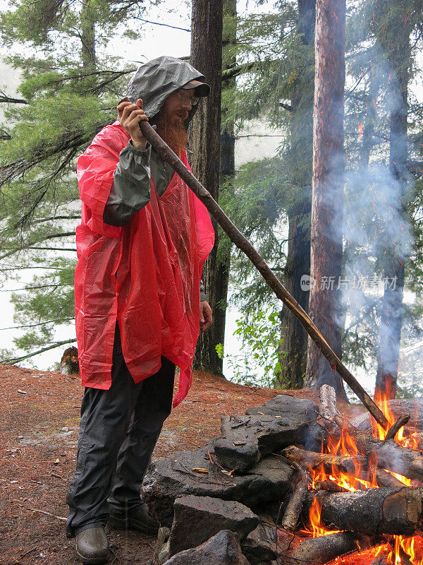 胡子眼镜男，红色雨夹克，照料营火