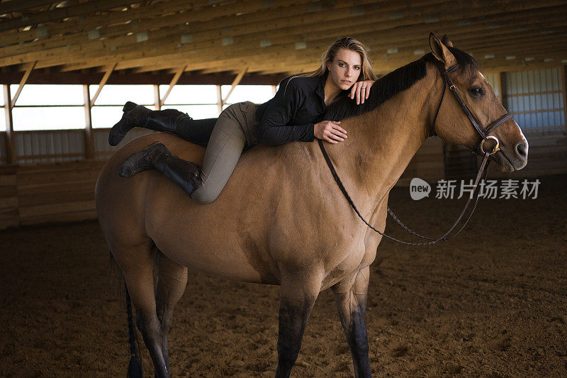 性感的金发躺在她的马赤裸的背部