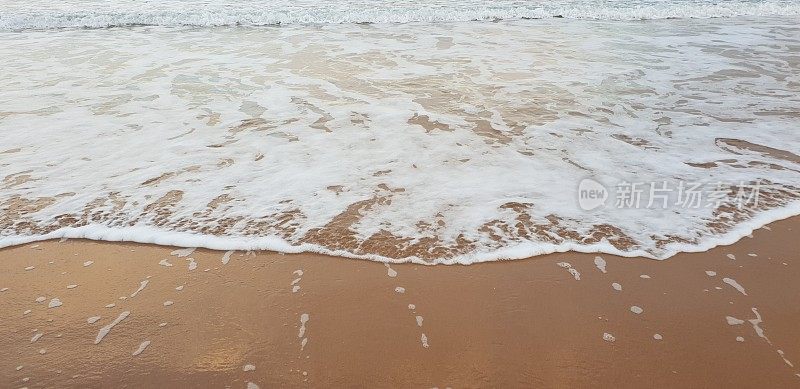 泡沫状的白色海浪拍打着海滩