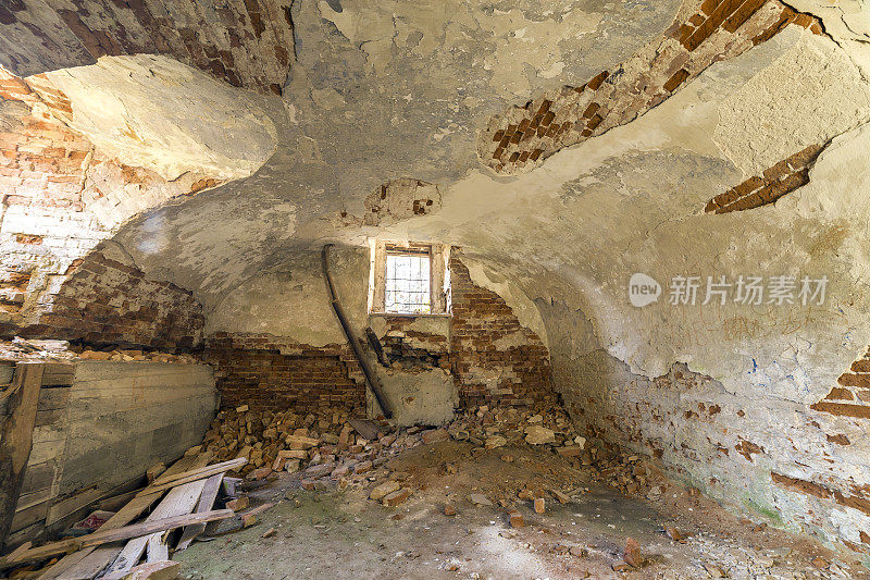 古老建筑或宫殿的废弃废弃的空地下室，灰泥墙开裂，低矮的拱形天花板，带铁条的小窗户，肮脏的地板。