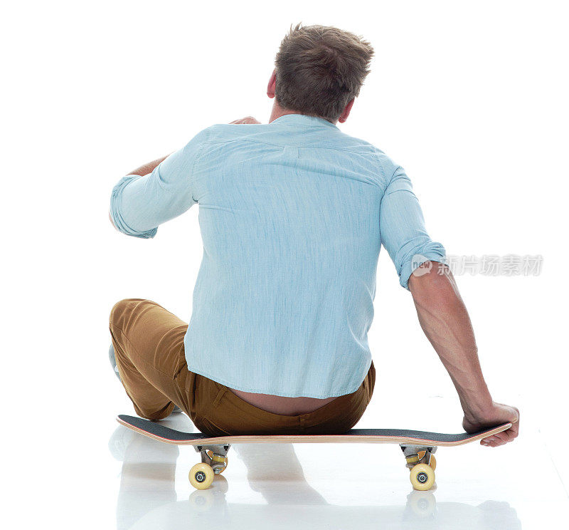 穿着随意，坐在滑板上的男人