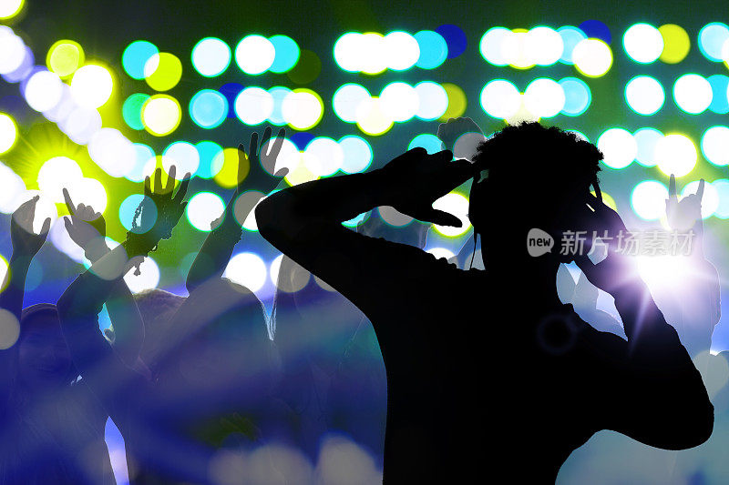 夜总会音乐会迪斯科DJ戴着耳机看着跳舞的人群