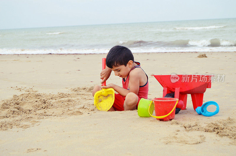 在英国的沙滩上玩沙滩玩具的小孩
