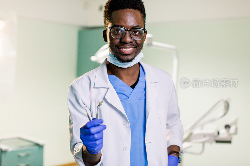 年轻男性非裔美国牙医穿着制服在他的工作地点牙科诊所
