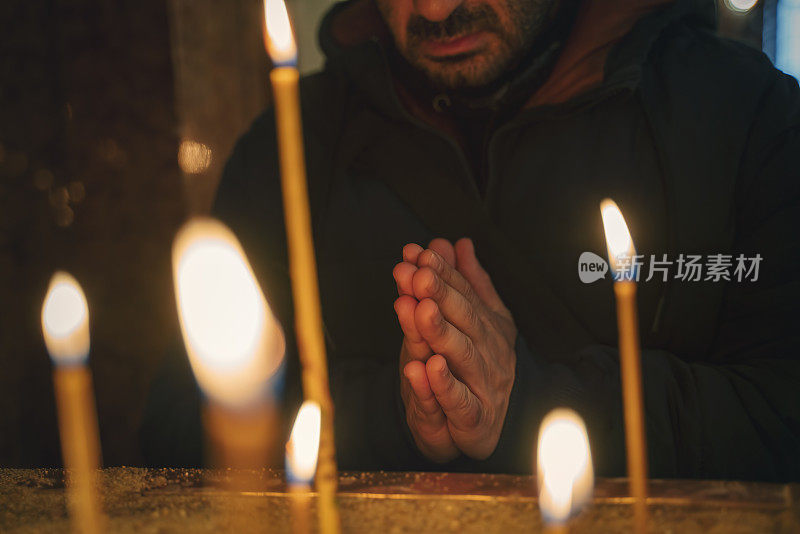 男人在教堂祈祷，蜡烛在大教堂，希望的概念