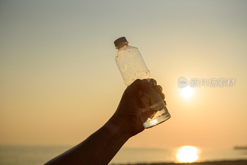 在夕阳下，男人手里拿着水晶般清澈的水瓶