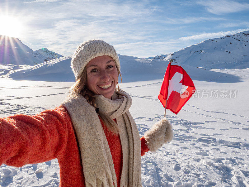 一名女子在瑞士阿尔卑斯山白雪皑皑的山上与瑞士国旗自拍