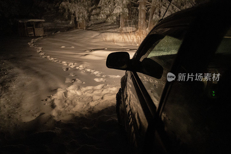 司机POV在积雪覆盖的道路上行驶，初雪飘落。被前灯和前车的红绿灯照亮的路。