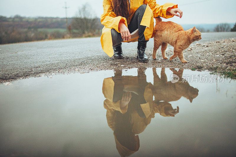 快乐的女孩和猫在大自然的雨