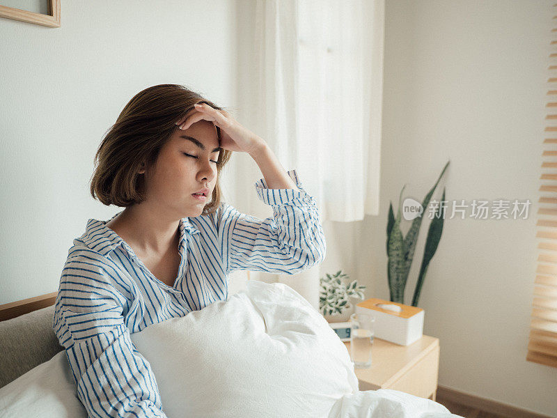 一位亚洲妇女得了流感，在家卧床饮水。