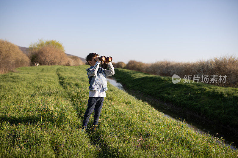 一个男孩透过双筒望远镜看