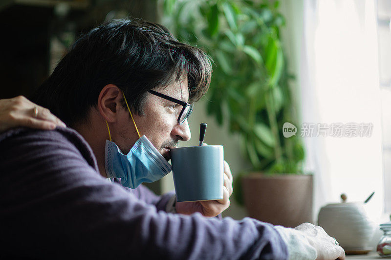 男子早上在厨房生病，戴着防护口罩，精疲力竭的病毒疾病