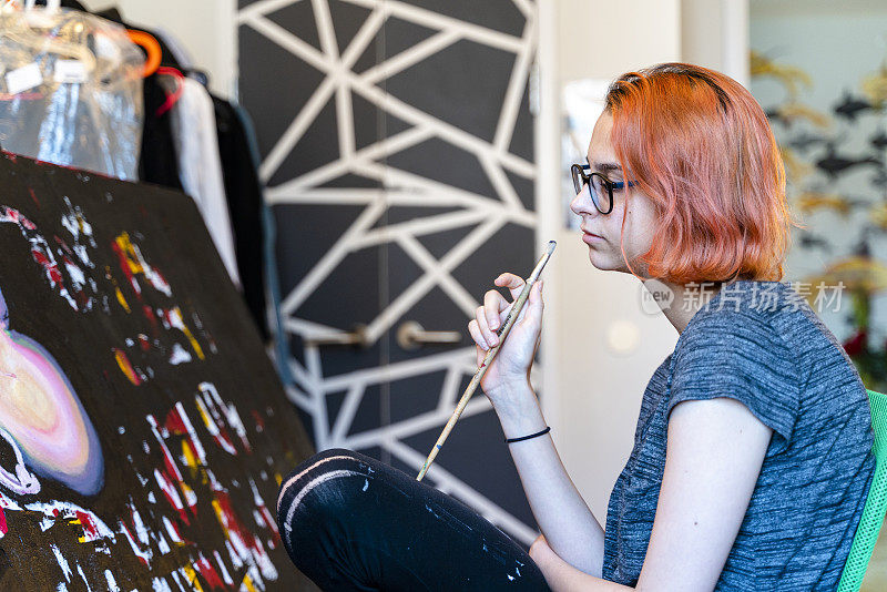 红发白人少女，艺术家，在她的房间里用油画颜料作画。