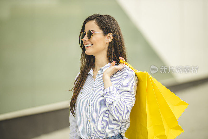 年轻漂亮的女人提着购物袋走路