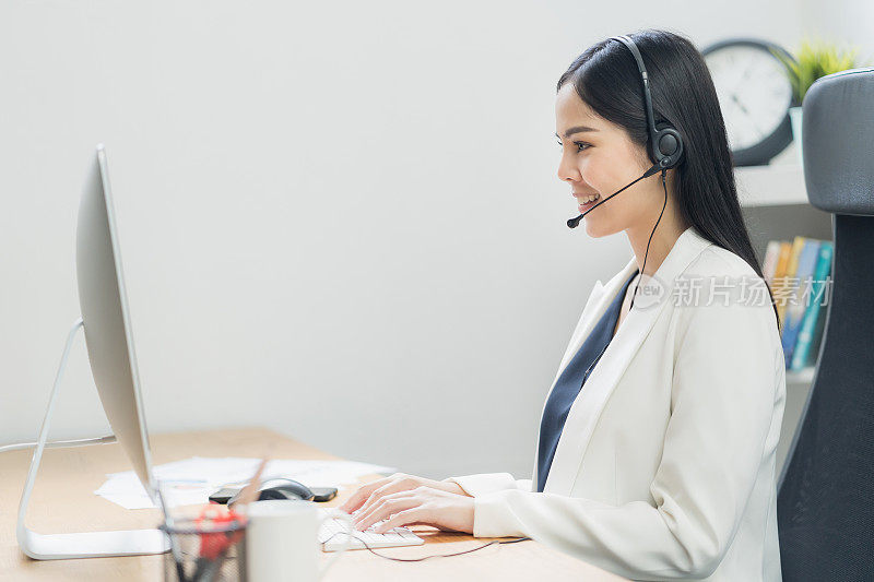 年轻的商业亚洲女性工作呼叫中心客户服务代理。有电脑和耳机的商务女性支持操作员在办公室。