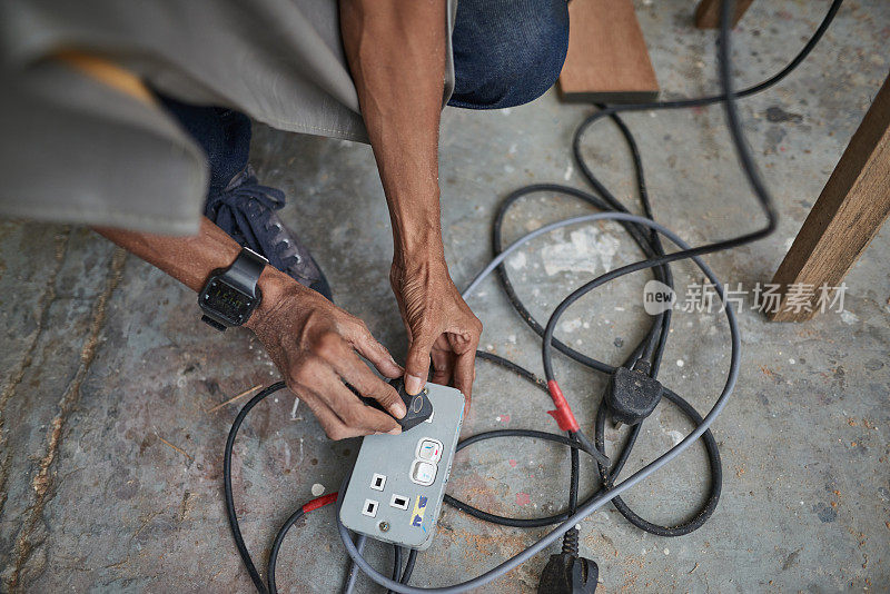 亚洲男性木匠特写亚洲熟练的工匠插入在多插头插座为他的木工工作在他的车库