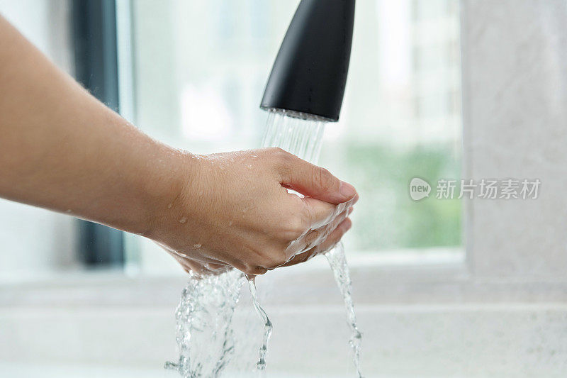 在自来水下洗手的女人