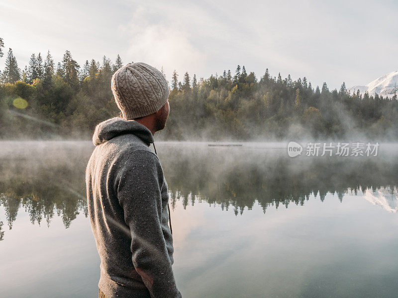 一名男子在木码头上休息，眺望着湖面