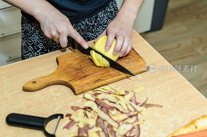 一位女厨师正在厨房里削生土豆。