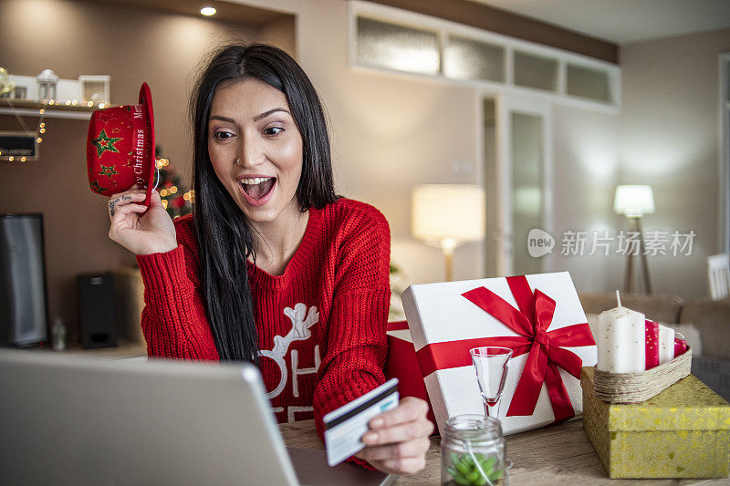 女人用信用卡在家里买新年的礼物-圣诞购物-一个年轻女人在网上买礼物的特写