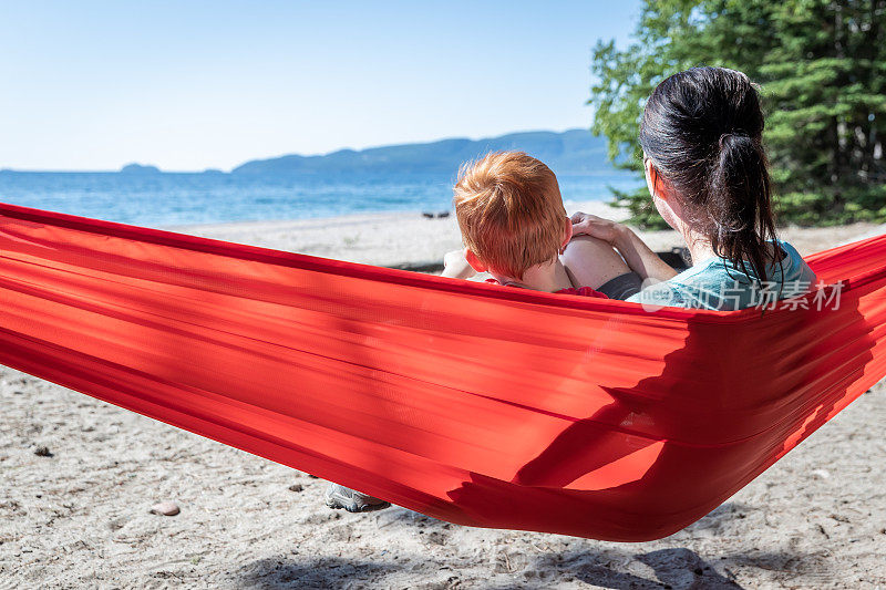 母亲和儿子有乐趣在红色吊床露营在夏天，安大略省，加拿大
