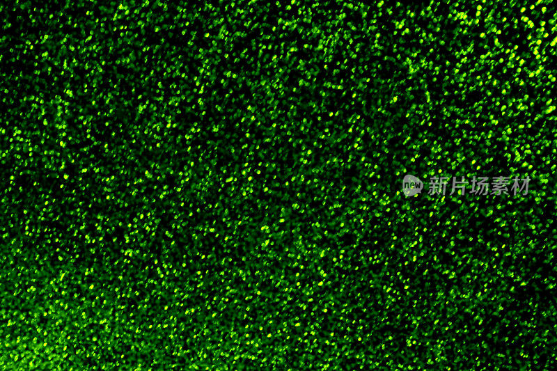 绿色闪烁圣诞图案抽象散景尘埃粒子黑色背景假日纹理微距摄影