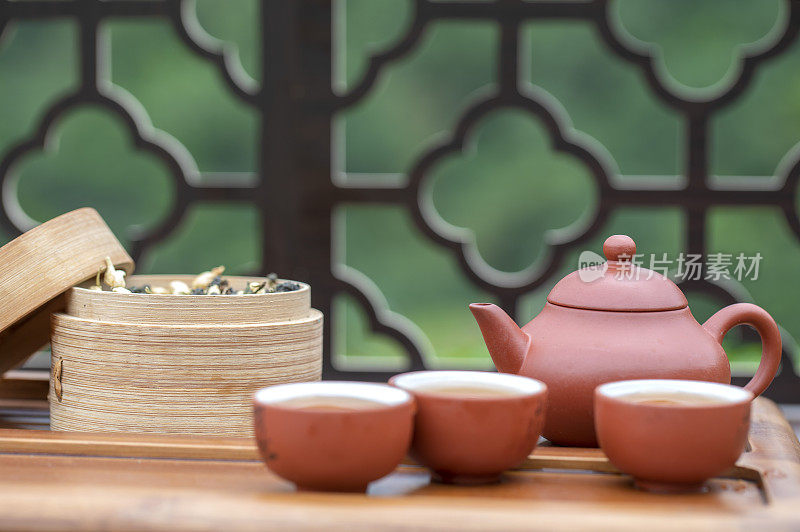 月光下窗花旁桌上的中国茶壶和茶杯富有禅意