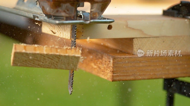 MACRO:当拼图锯切割工件时，锯末从金属刀片上飞落。
