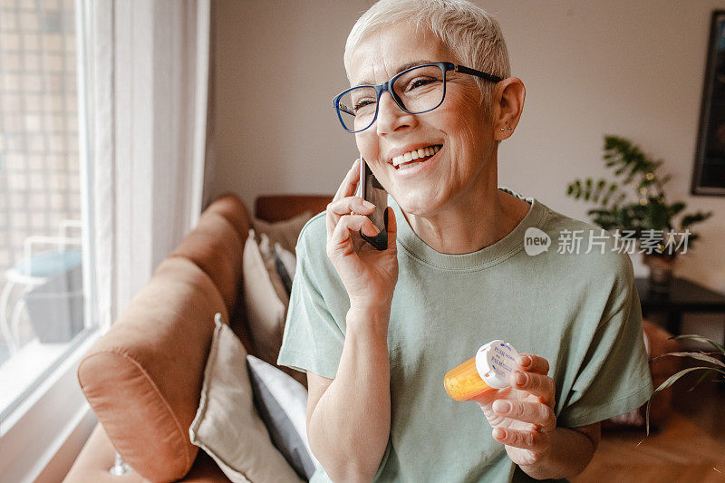 一位老年妇女打电话给健康服务部门，在她手里拿着一瓶药的同时寻求医疗建议