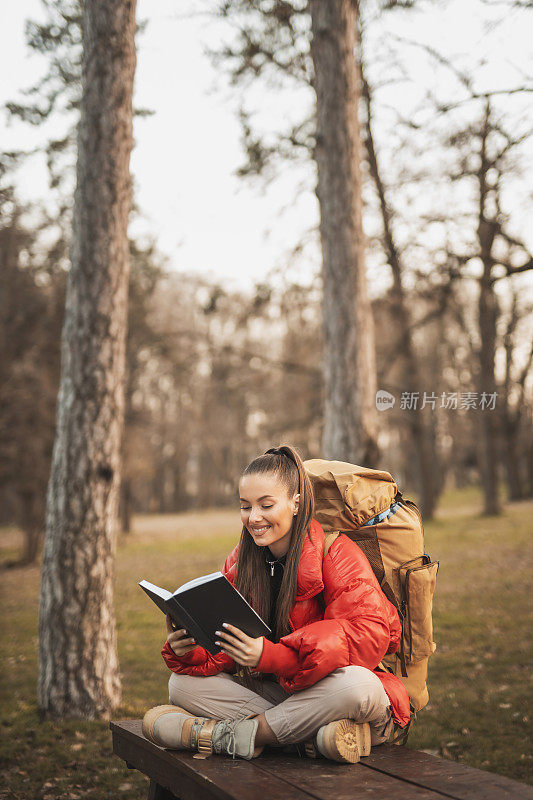 女人在山里徒步旅行时休息和阅读一本书