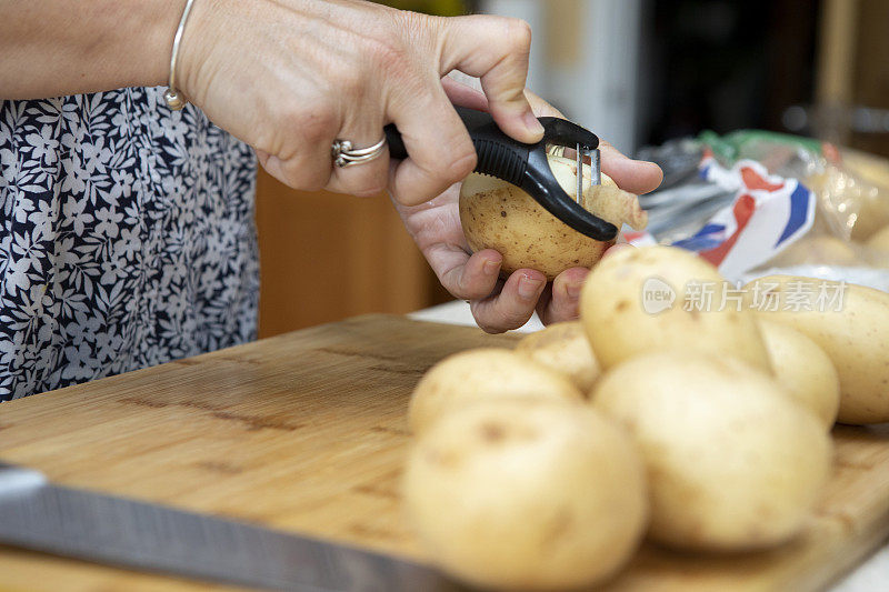 特写镜头是女性的手在木制砧板上削土豆