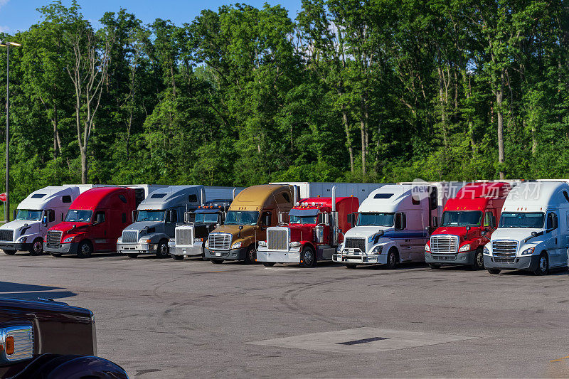 不同型号的工业级专业大卡车半挂车在卡车停车停车场排成一排。
