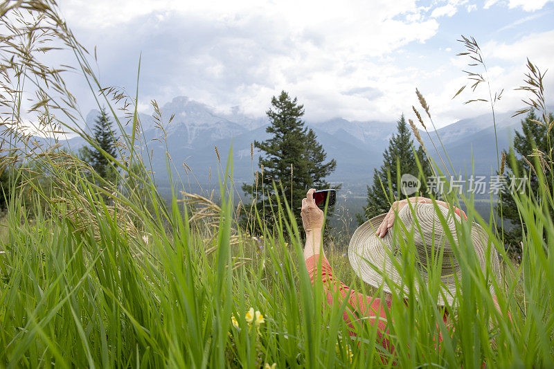 戴太阳帽的成熟女人在草地上使用手机