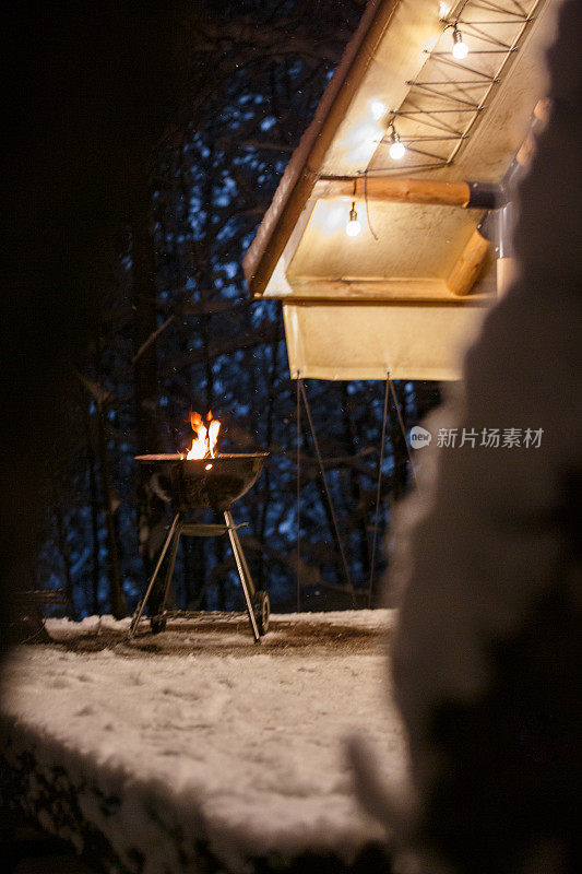 冬天，在房子旁边的街道上，一个烧烤架的特写，美味的香肠在上面炸。