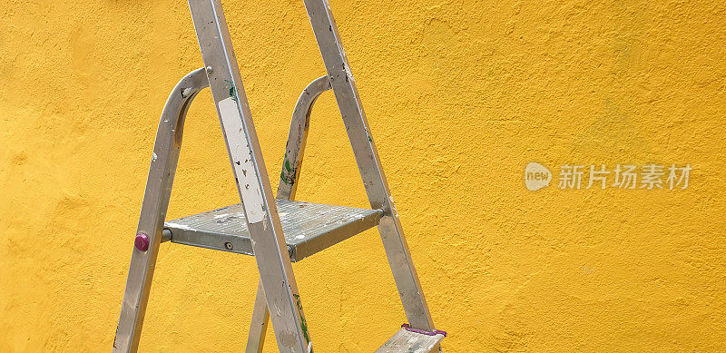 梯子靠在新粉刷的黄色墙壁上