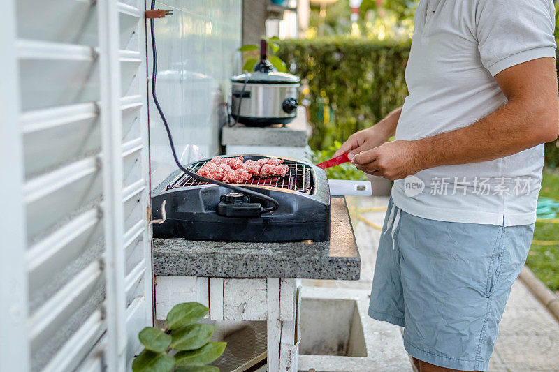 男性用手在烧烤架上翻动肉